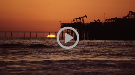 A sunset behind an ocean oil rig 