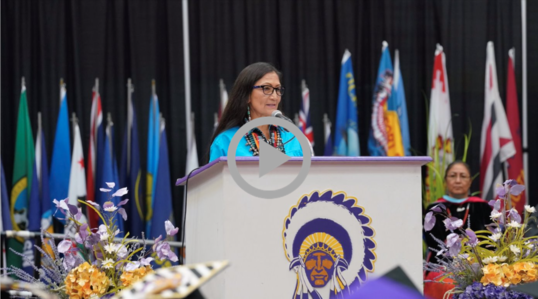 Secretary Haaland speaking behind a podium Haskell Indian Nations University