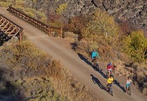 Bike riders on a trail next to a rock formation.