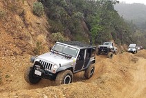 Jeeps driving on a rough dirt trail.