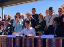 Secretary Haaland signs a document while people watch.