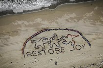 Restore Joy Spelled out in the sand by people.