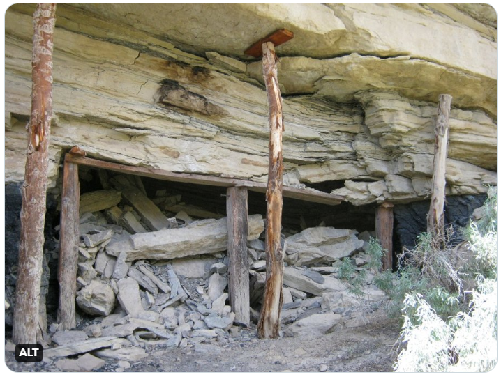 Layers of rock are propped up by beams of support. The ruins of an old mine are crumbling 