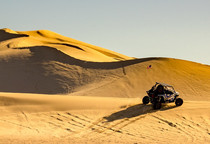 A dune buggy on a large sand dune.