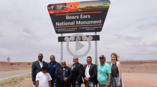 Federal, local and Tribal leaders stand smiling under new Bears Ears National Monument sign