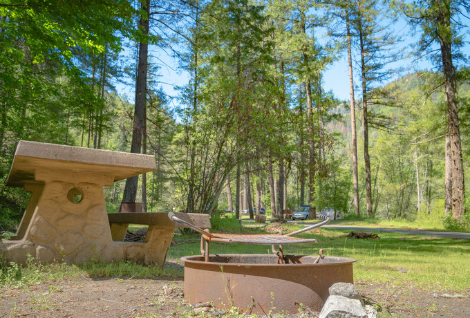 A campground with a picnic table and fire ring.