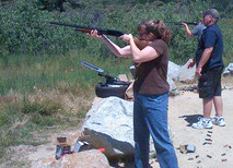A Lady shooting a shotgun.