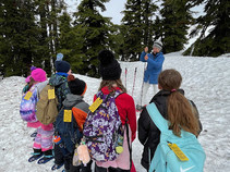 A teacher teaching kids in snow with skiing equipment.