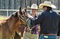 A woman and man in cowboy hats next to a horse.