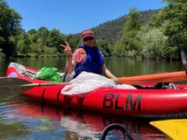A person in a BLM kayak giving a peace sign.