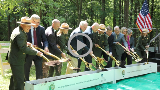 Federal, state, and local leaders use ceremonial shovels to move dirt at groundbreaking event