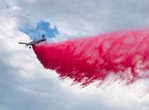 An airplane dropping retardant on a burning field.