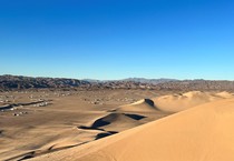 Large sand dunes with vehicles parked in the valley.