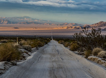 A dirt road going off in the distance towards a desert.