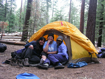 Three people in a yellow tent.