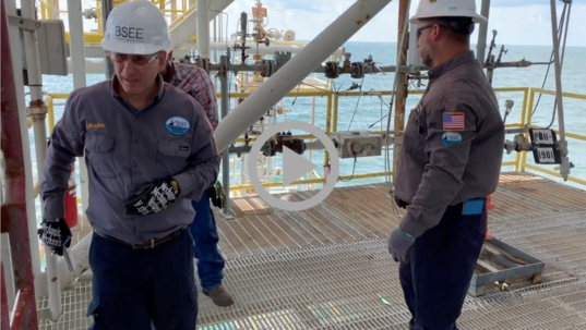 Two safety inspectors wearing helmets examine an offshore oil rig