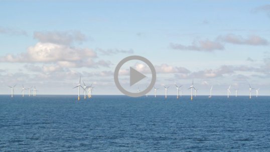 A line of ocean wind turbines against the sky