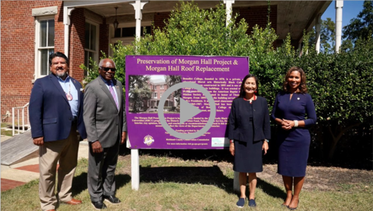 Secretary Haaland and National Park Service Director Sams join others in front of a sign at Morgan Hall on the campus of Benedict College