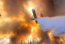 An air tanker dropping water on a fire.