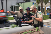 Three officers look at a map on the hood of a truck.
