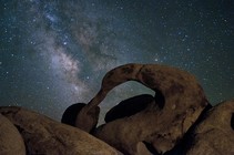 A rock formation in front of the night sky featuring the Milky Way.