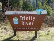 Trinity River, National Wild & Scenic River Sign in front of shrubs and trees
