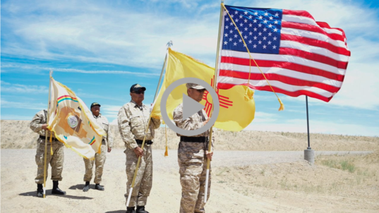 Native men wearing military uniforms hold Tribal and U.S. flags 