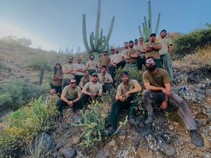 A group of firefighters sitting on a hillside with cacti.