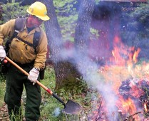 A fire fighter burning a pile of brush.