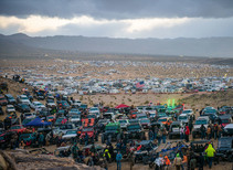 A vast desert landscape filled with off-highway vehicles and people.