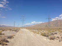A dirt road in the desert with a parallel transmission line.