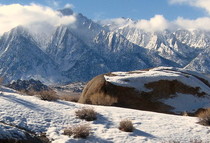 Alabama Hills’ granite rock has been etched by wind and water covered in snow with high clouds. 