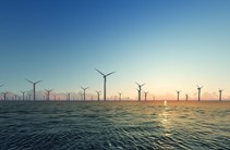 Several offshore-wind turbines extend above the ocean's waters. 