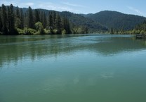 Klamath River basin's large expanse of calm river waters lined with hills covered in trees. 