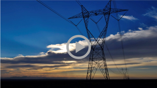 A transmission tower and power lines at sunset