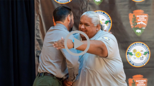A National Park Service official embraces a member of the Twenty-Nine Palms Band of Mission Indians at a ceremony.