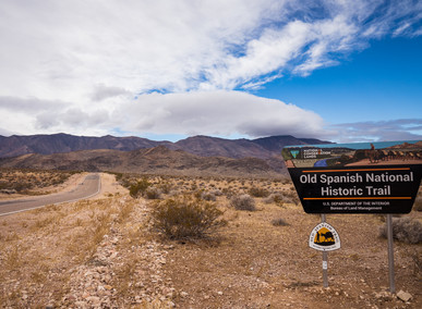 Old Spanish National Historic Trail sign on the side of the road with mountains in the distance 