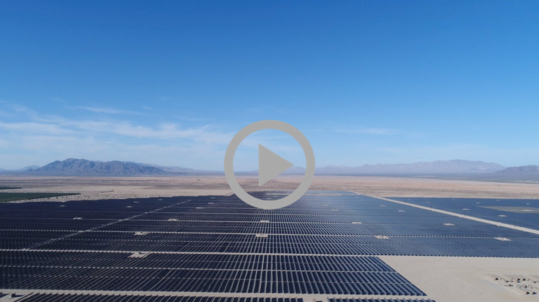 A large solar energy array stretches across a desert landscape