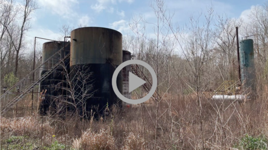 Abandoned and rusting oil tanks in a thicket of woods