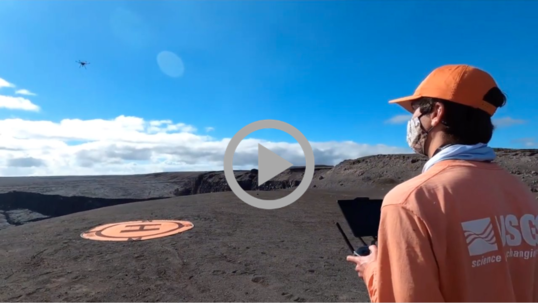 A USGS field scientist operates a drone above a volcano.