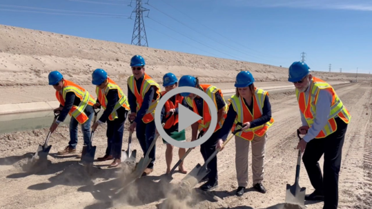 Bureau of Reclamation Commissioner Camille Calimlim Touton and others take part in a ceremonial groundbreaking, wearing vests and helmets. 