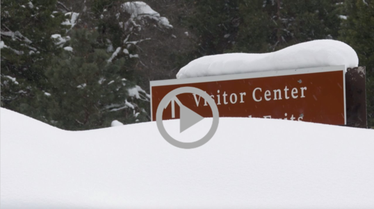 Deep snow drifts rise to halfway up a Visitor Center sign at a California national park