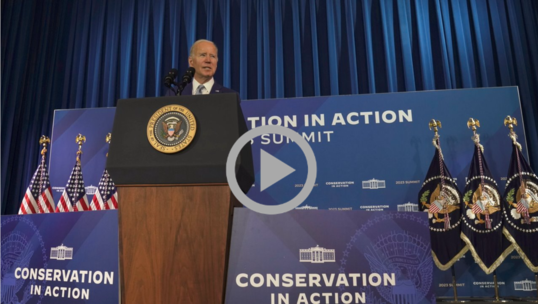President Biden speaks from behind a podium bearing the Presidential Seal at the White House Conservation Summit. 