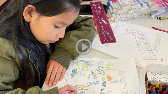 A child colors on a drawing with Landsat imagery
