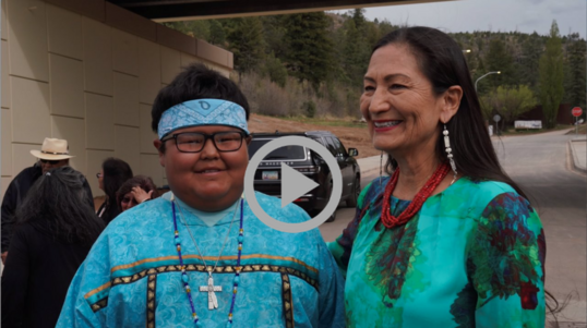 Secretary Haaland stands next to a young member of the Mescalero Apache Tribal community.