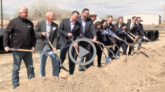 Dignitaries holding shovels take part in a groundbreaking ceremony.
