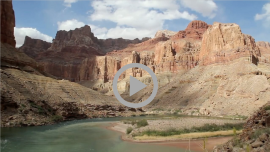The Colorado River flows through a canyon of high rocky bluffs that show age-old signs of erosion. 