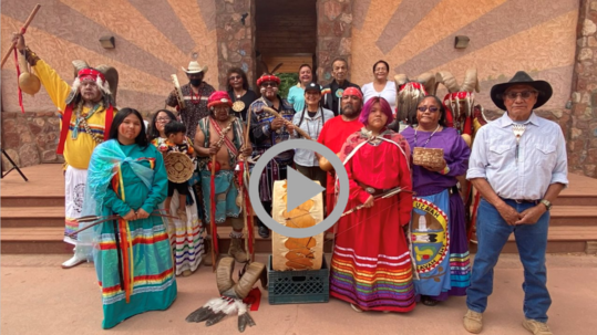 Secretary Haaland poses with Tribal members wearing traditional clothing and regalia and carrying artifacts in the village of Supai. 