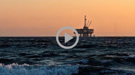 An offshore drilling rig viewed against an early evening sky.