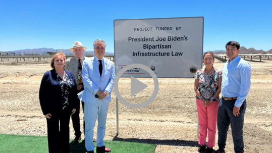 Secretary Haaland and others stand by a sign at the site of a water treatment plant. 